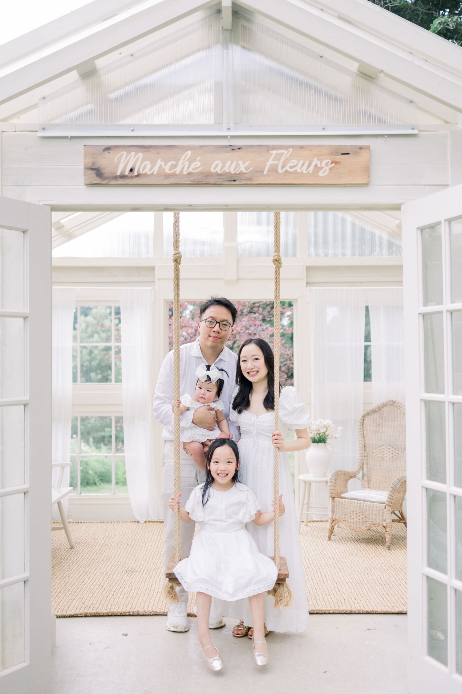 A bright white sunroom with glass windows, natural light, and beige carpeting features a simple swing seating arrangement.