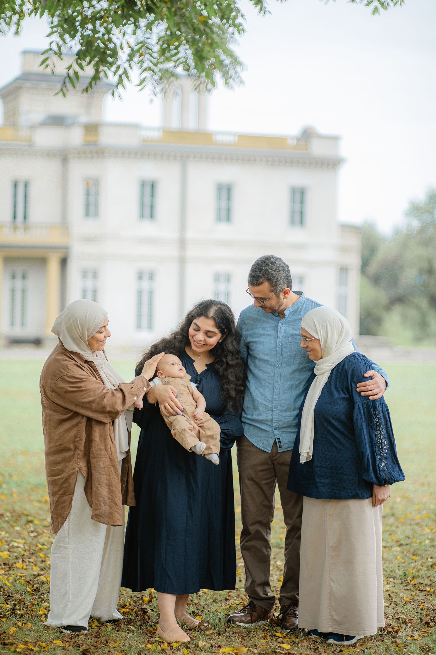 A multigenerational family gathering outside a grand white villa.