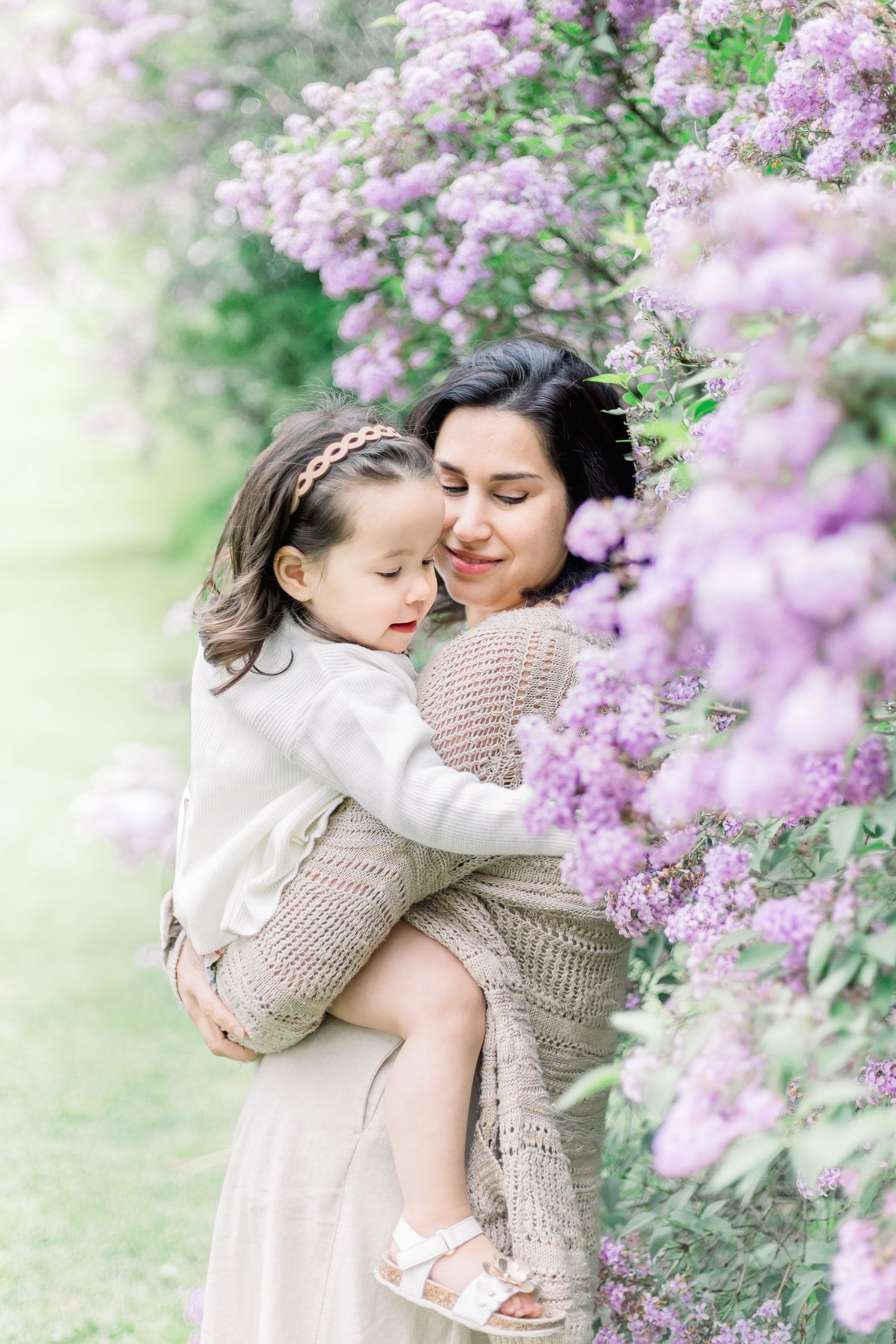 A tender embrace between parent and child surrounded by blooming lilac flowers in a spring garden.