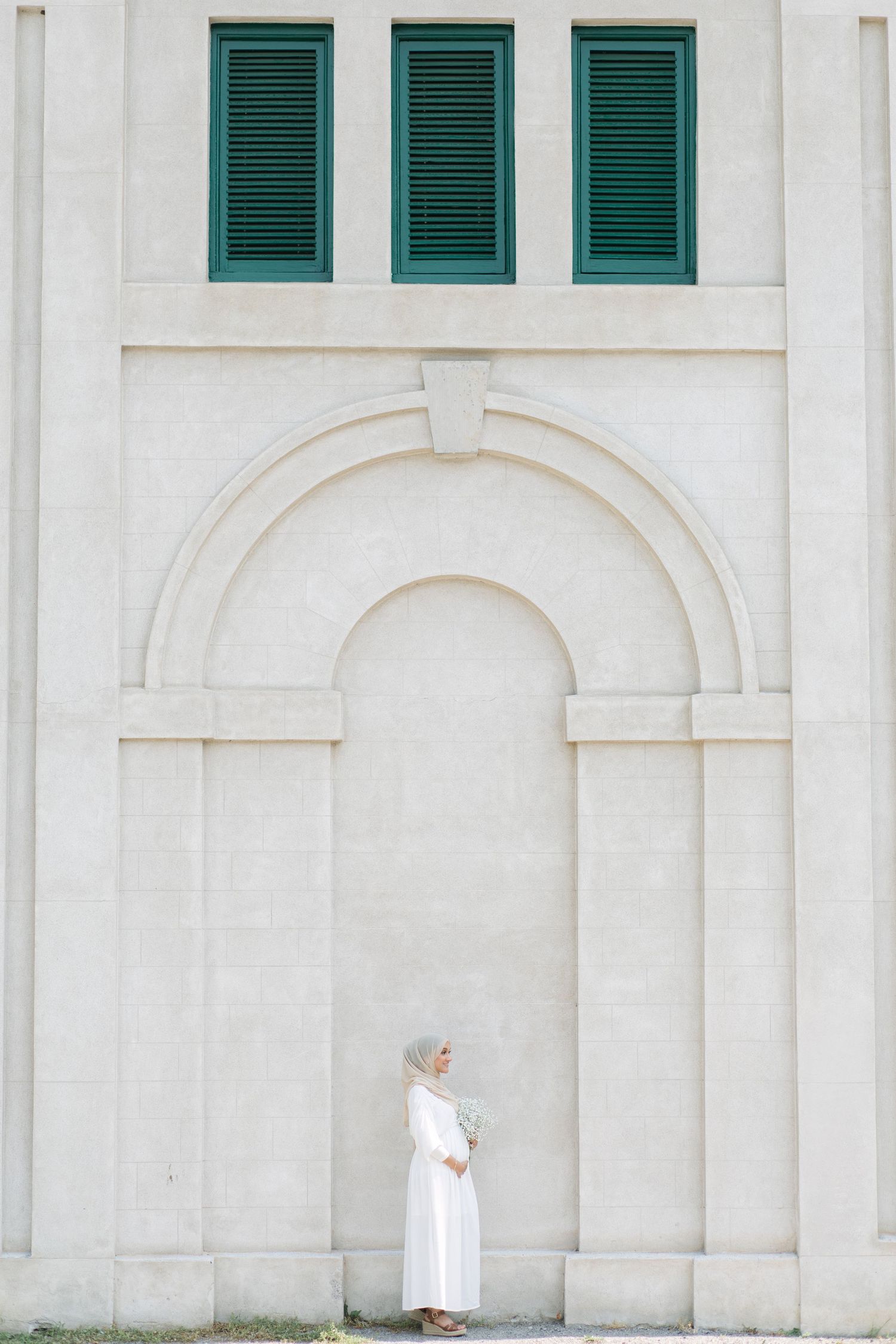 White building exterior with green shuttered windows and arched architectural details.
