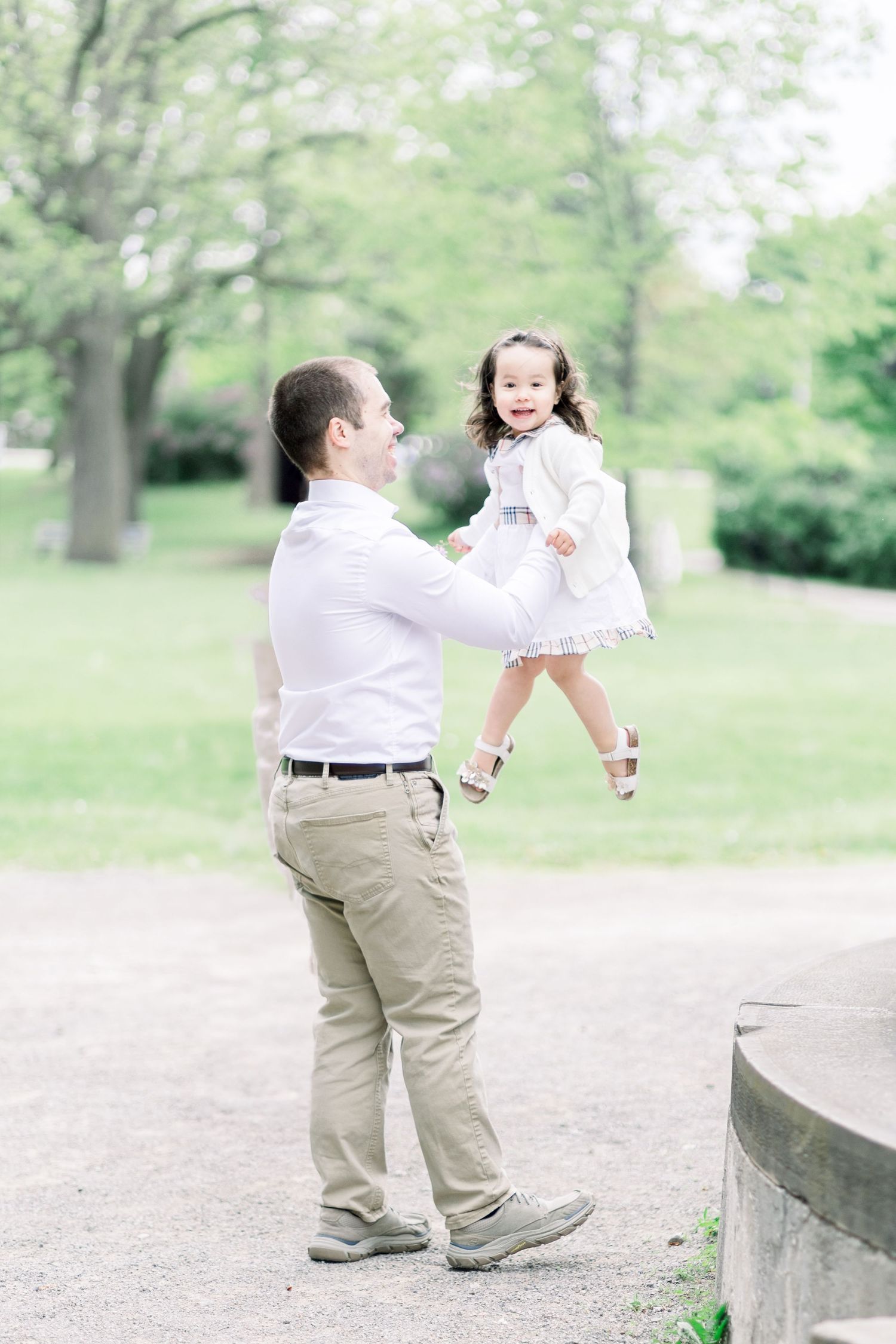 A heartwarming moment as small figures in white and khaki share playful interactions on a stone surface in a park setting.