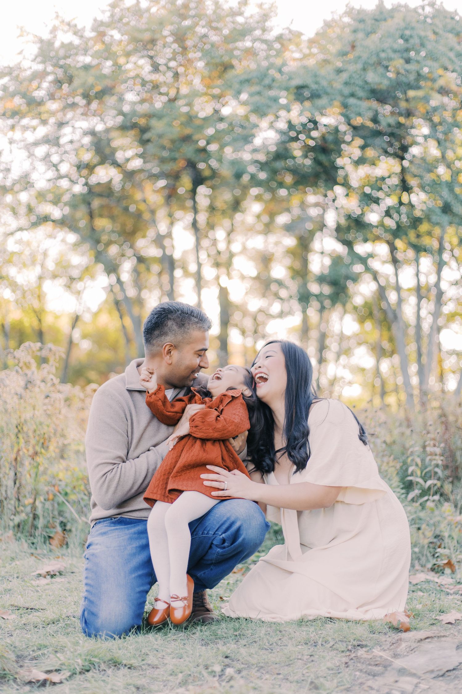 A heartwarming family moment captured in a golden-lit forest setting during autumn.