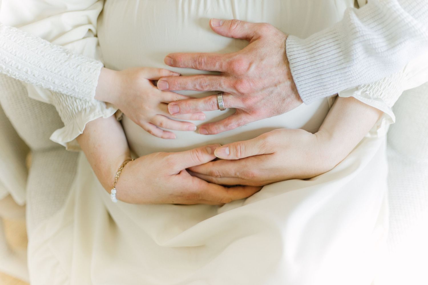 Hands gently holding and cupping a white porcelain bowl against a light neutral background.