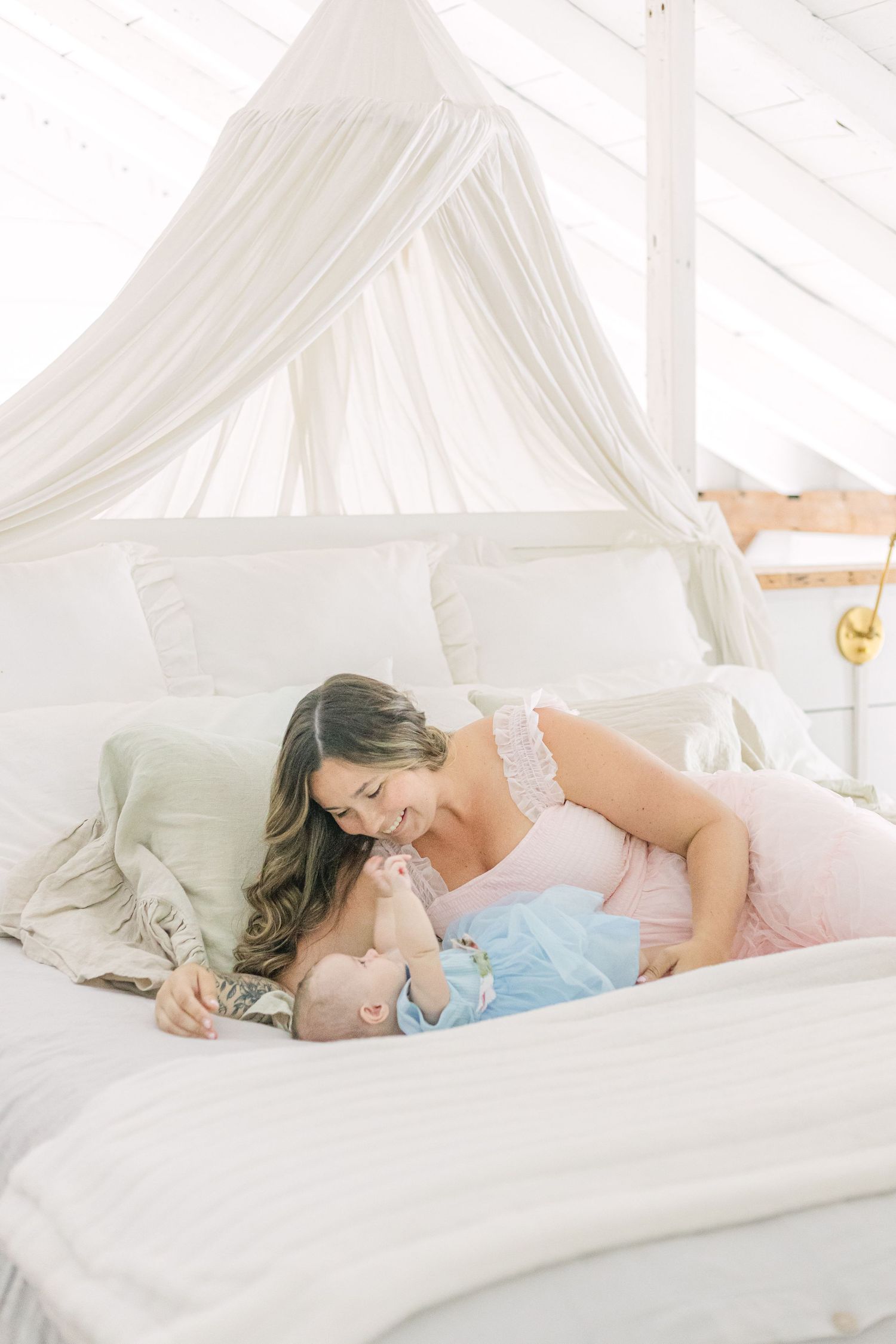 A tender moment between parent and child lying together on white bedding under a canopy.