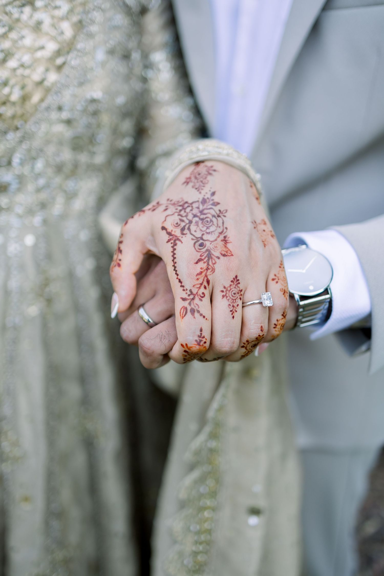 Close-up view of hands with intricate henna designs during a wedding ceremony.