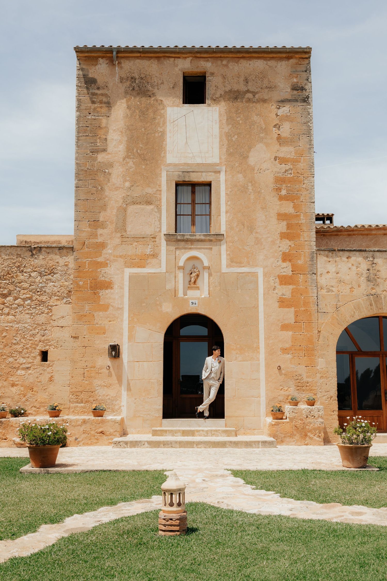 Mediterranean style stone building entrance with arched doorway and ornate facade in warm beige tones.