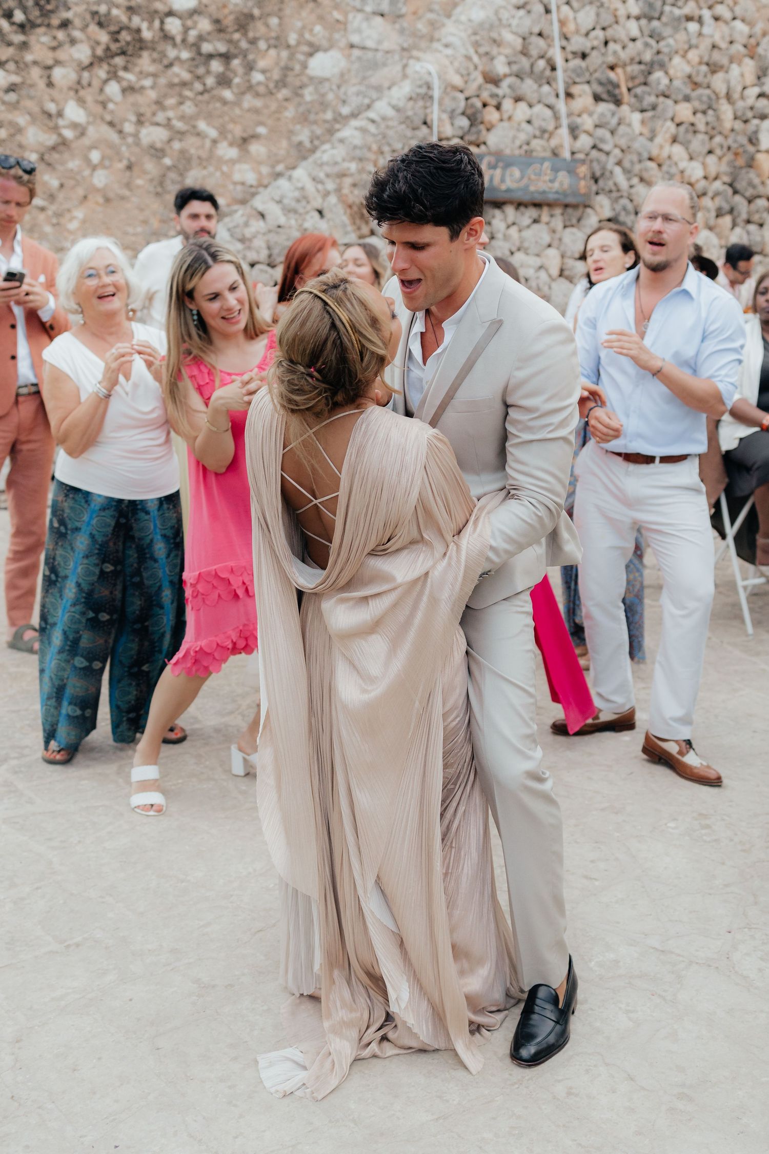 Wedding guests dancing and celebrating at outdoor venue.