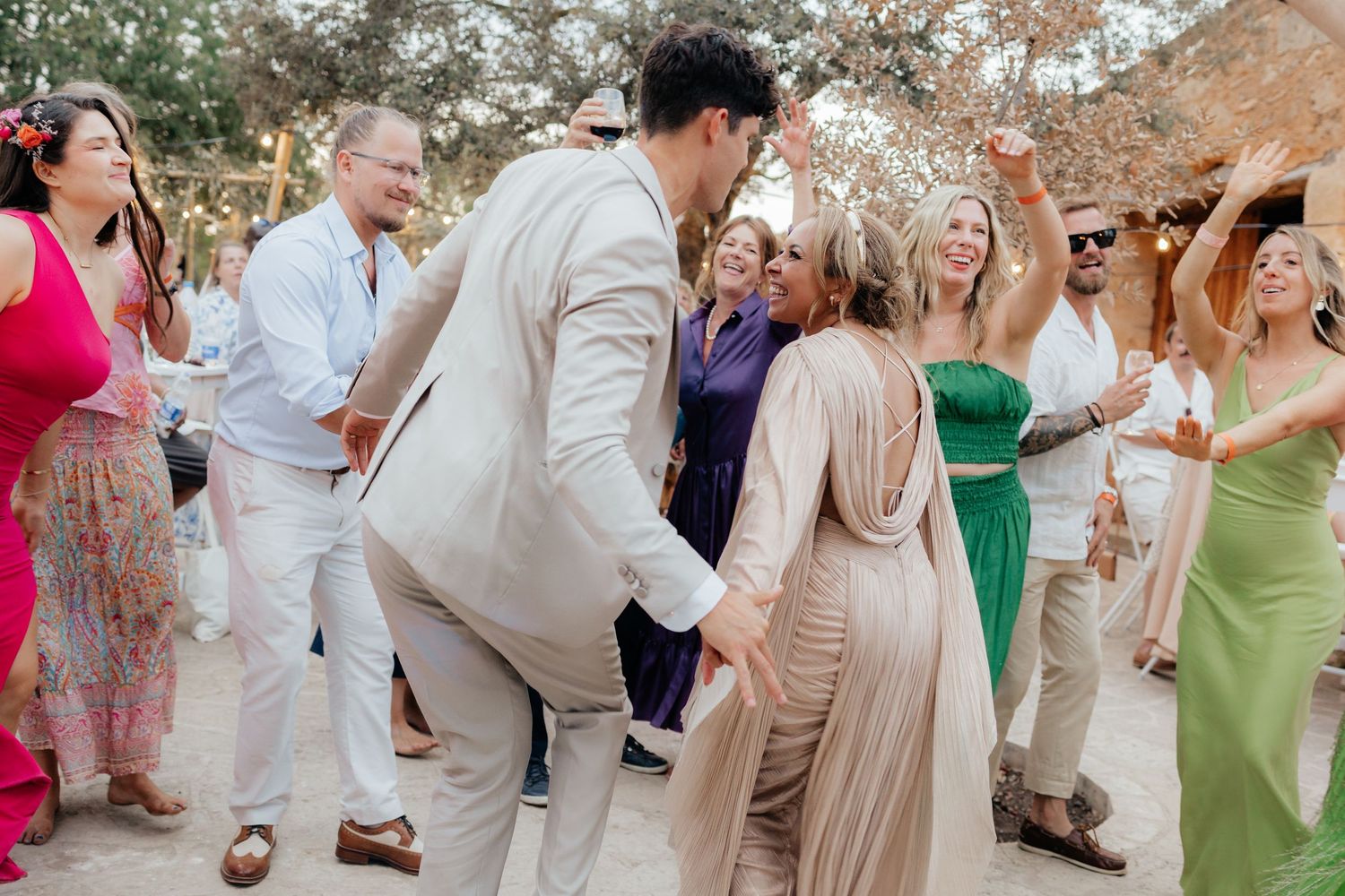 Wedding guests dancing and celebrating at an outdoor reception.