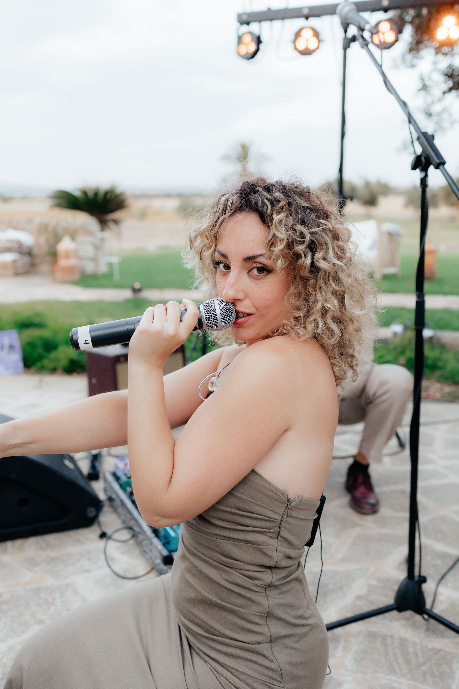 Singer performs at outdoor venue with stage lighting and microphone.