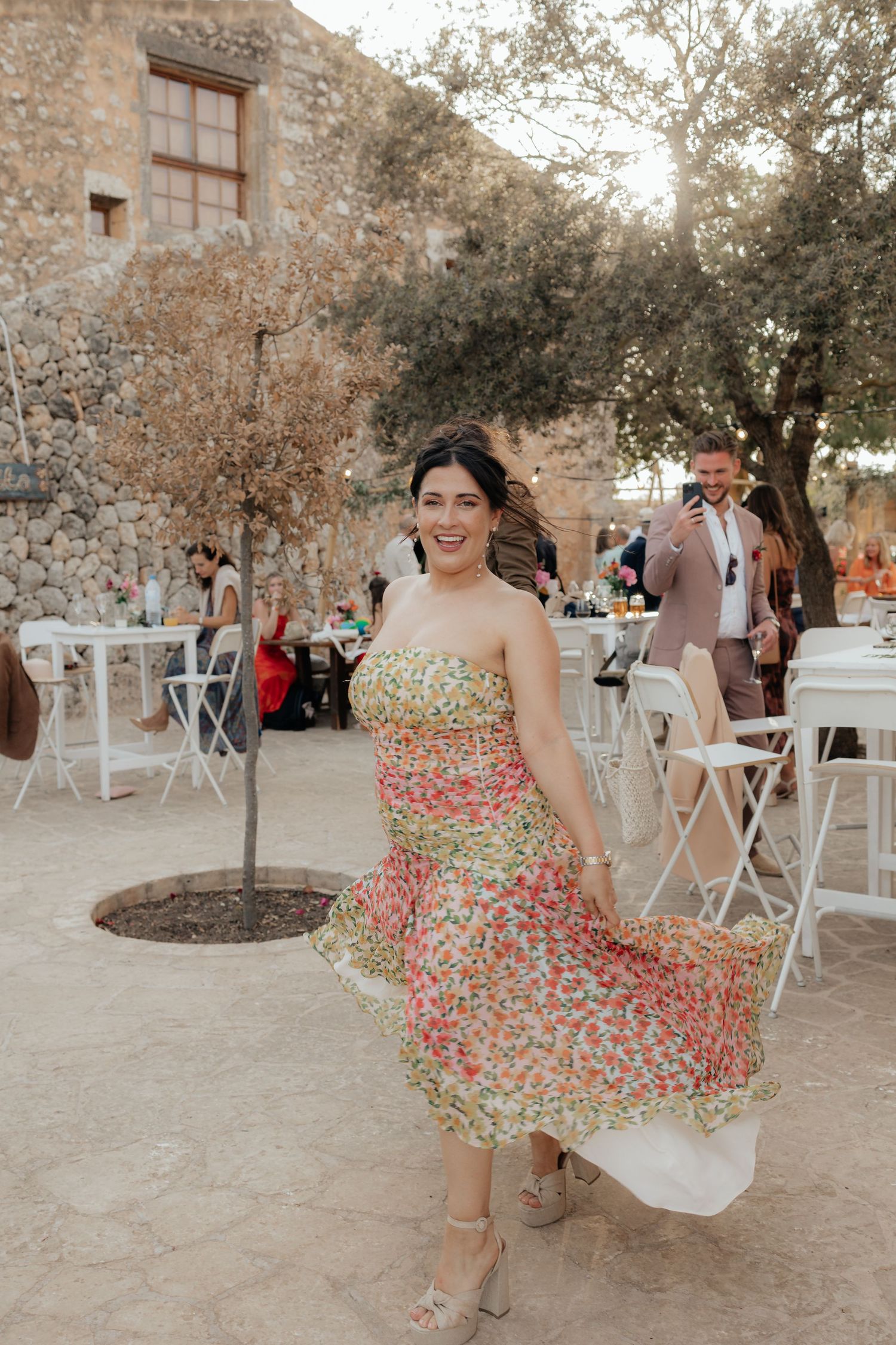 A flowing floral print dress twirls at an outdoor garden party venue.