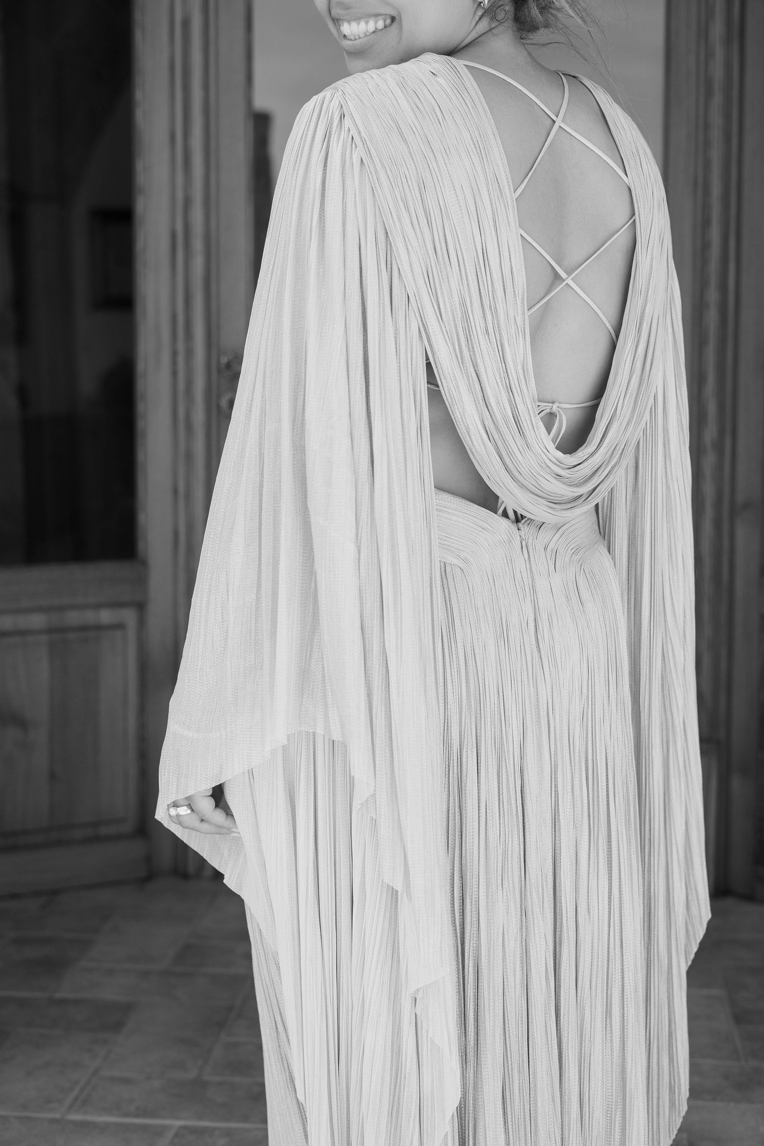 Elegant wedding dress with draped back detail and intricate straps in black and white.