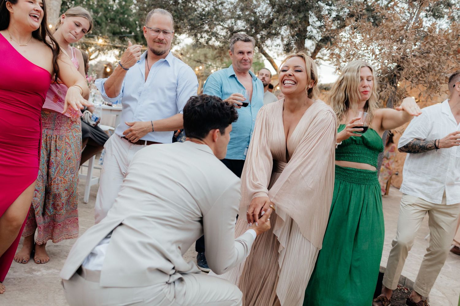 Joyful celebration with wedding guests in colorful dresses during outdoor reception.