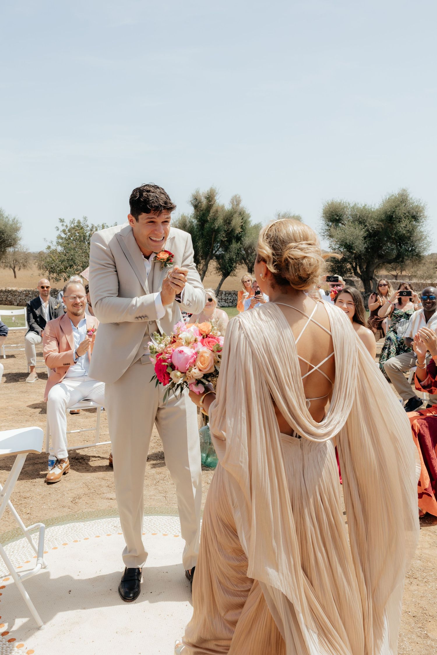 Wedding celebration outdoors with guests celebrating in light colored attire.