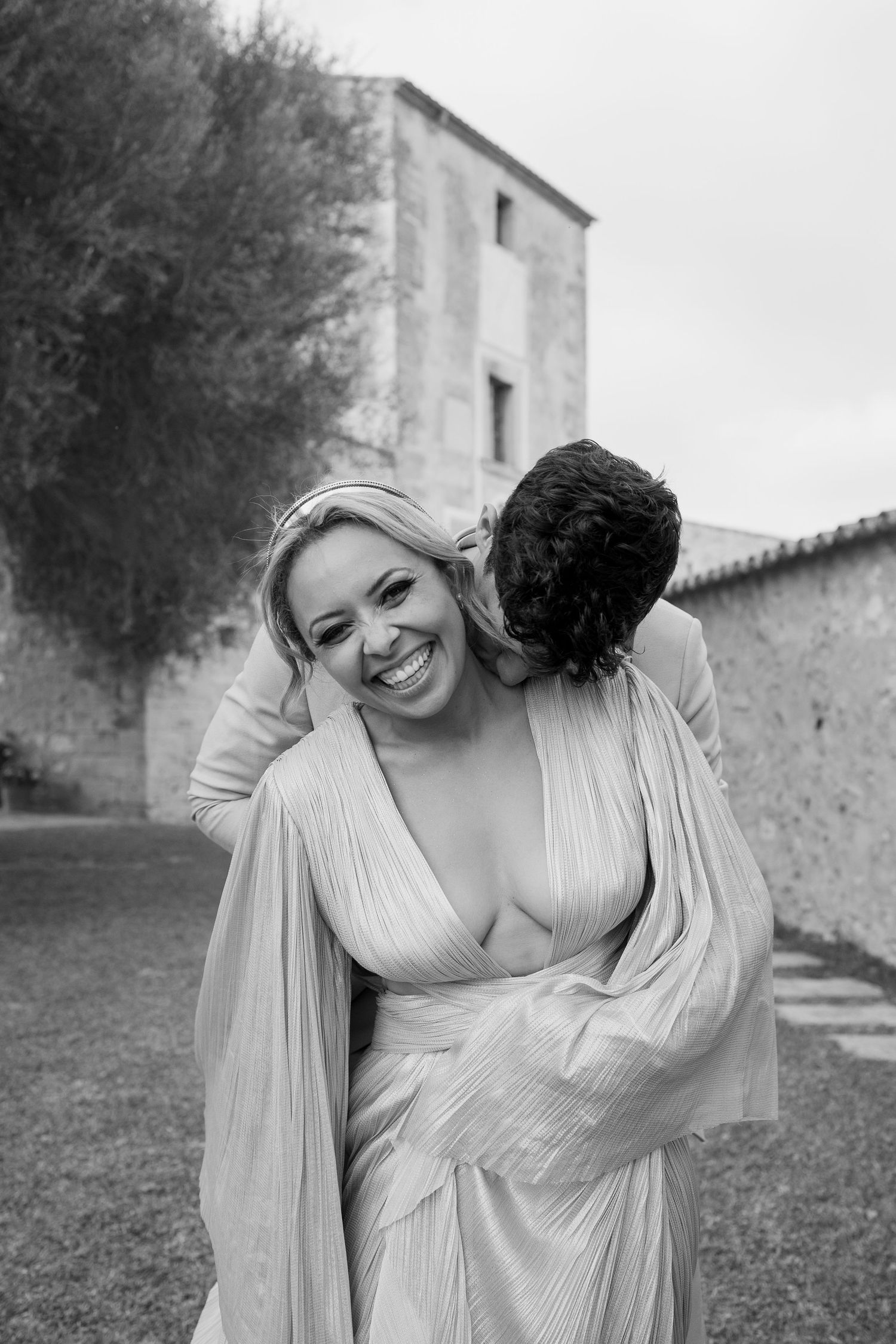 Joyful wedding moment captured in black and white against a rustic villa backdrop.
