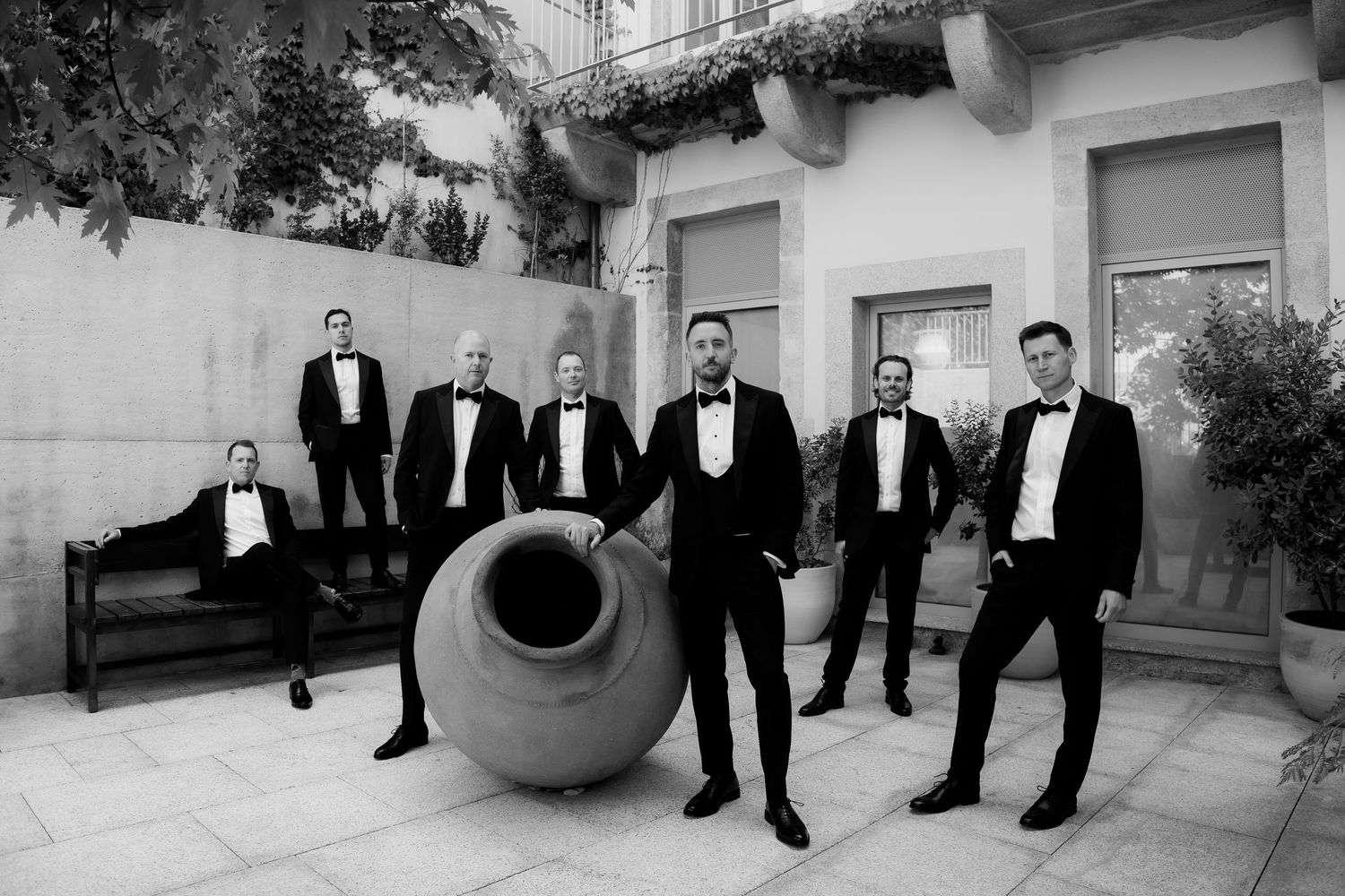 groom and groomsmen in black tuxedos posing in style