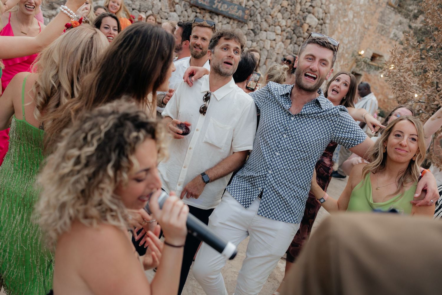 Lively group of guests dancing and celebrating together at an outdoor wedding event.