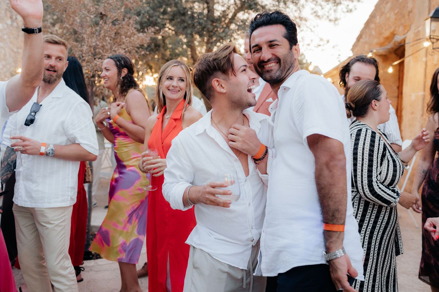 Joyful celebration at an evening wedding reception with guests in colorful attire.