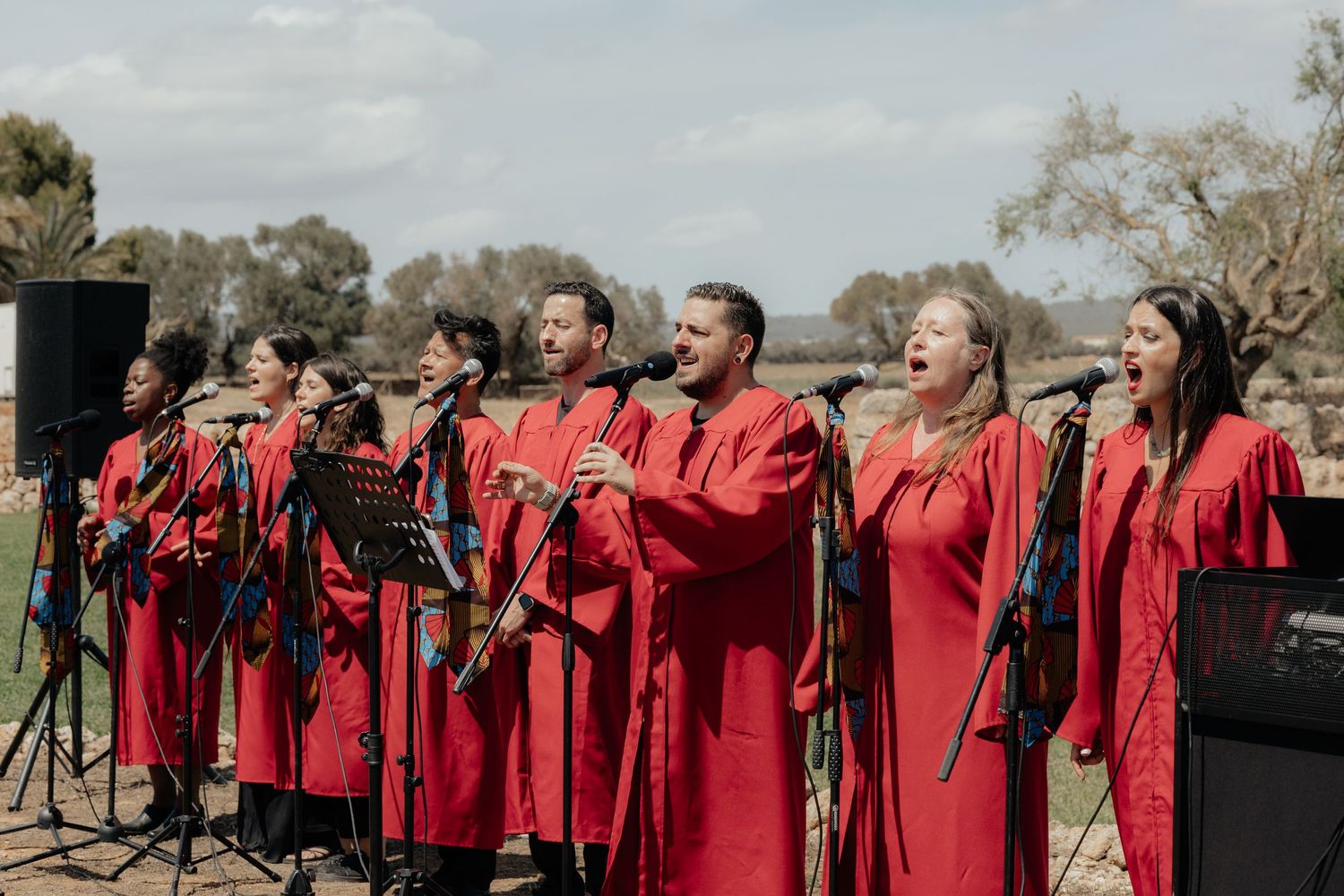 Gospel choir in bright red robes performs outdoors at an event.