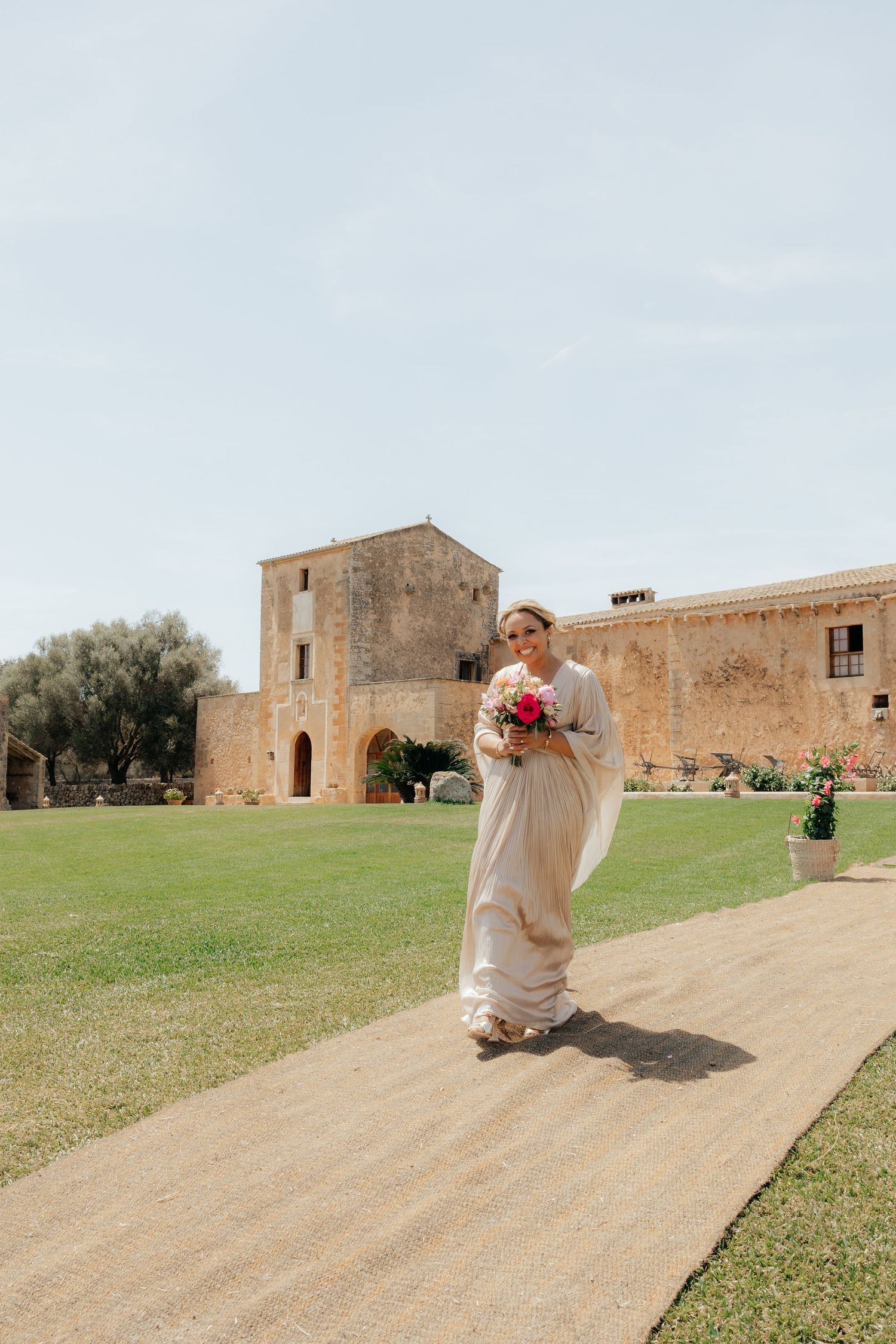 Person walking down a path carrying flowers at a historic stone building venue.