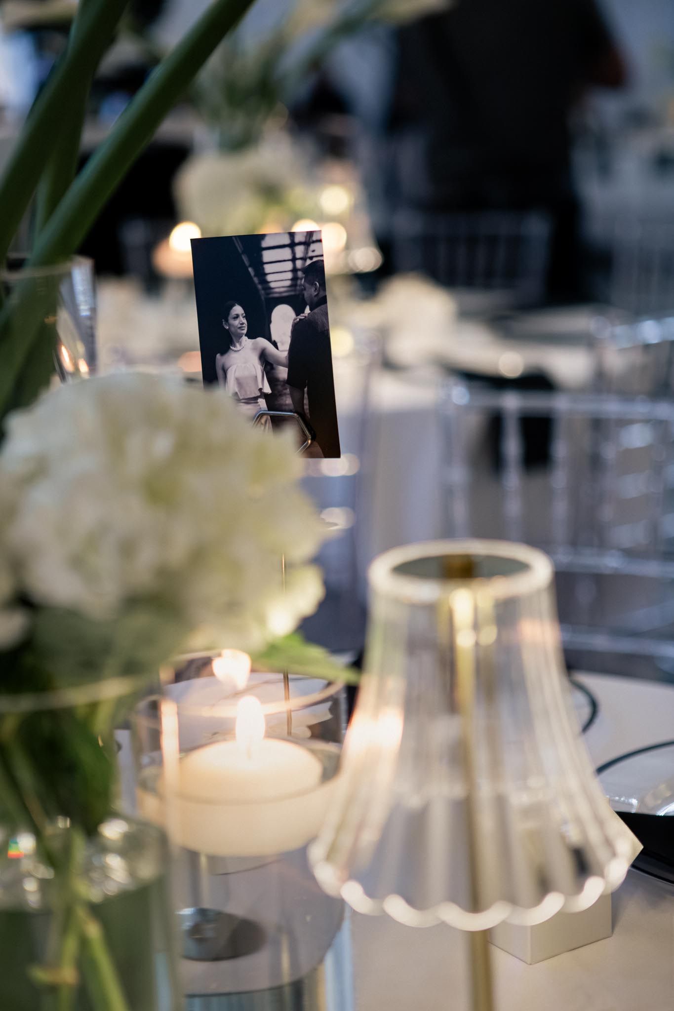 Mesa de boda decorada con flores blancas, velas encendidas y una fotografía en blanco y negro de la pareja.