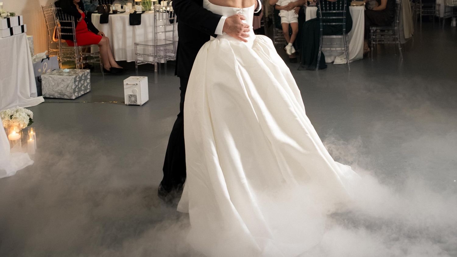 Novios abrazados durante su baile de boda, con el vestido blanco rodeado de humo bajo.