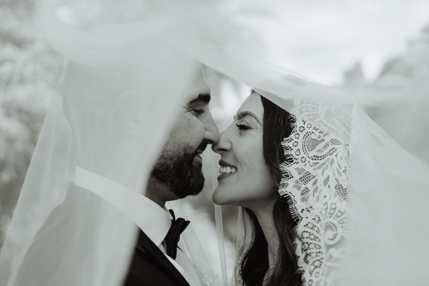 Bride and groom kissing beneath the veil, black and white wedding photograph