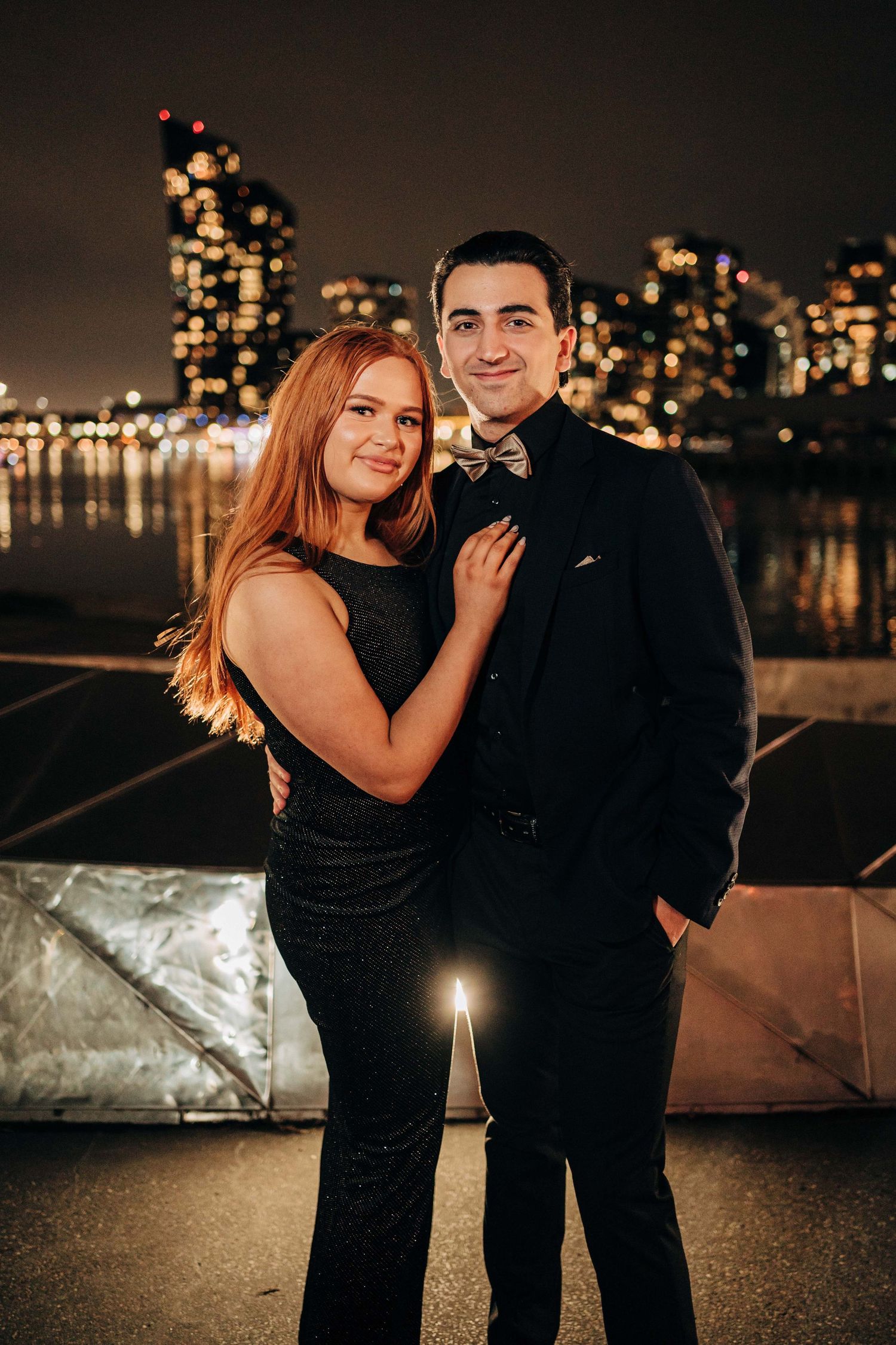 Couple at an evening celebration with city lights behind them