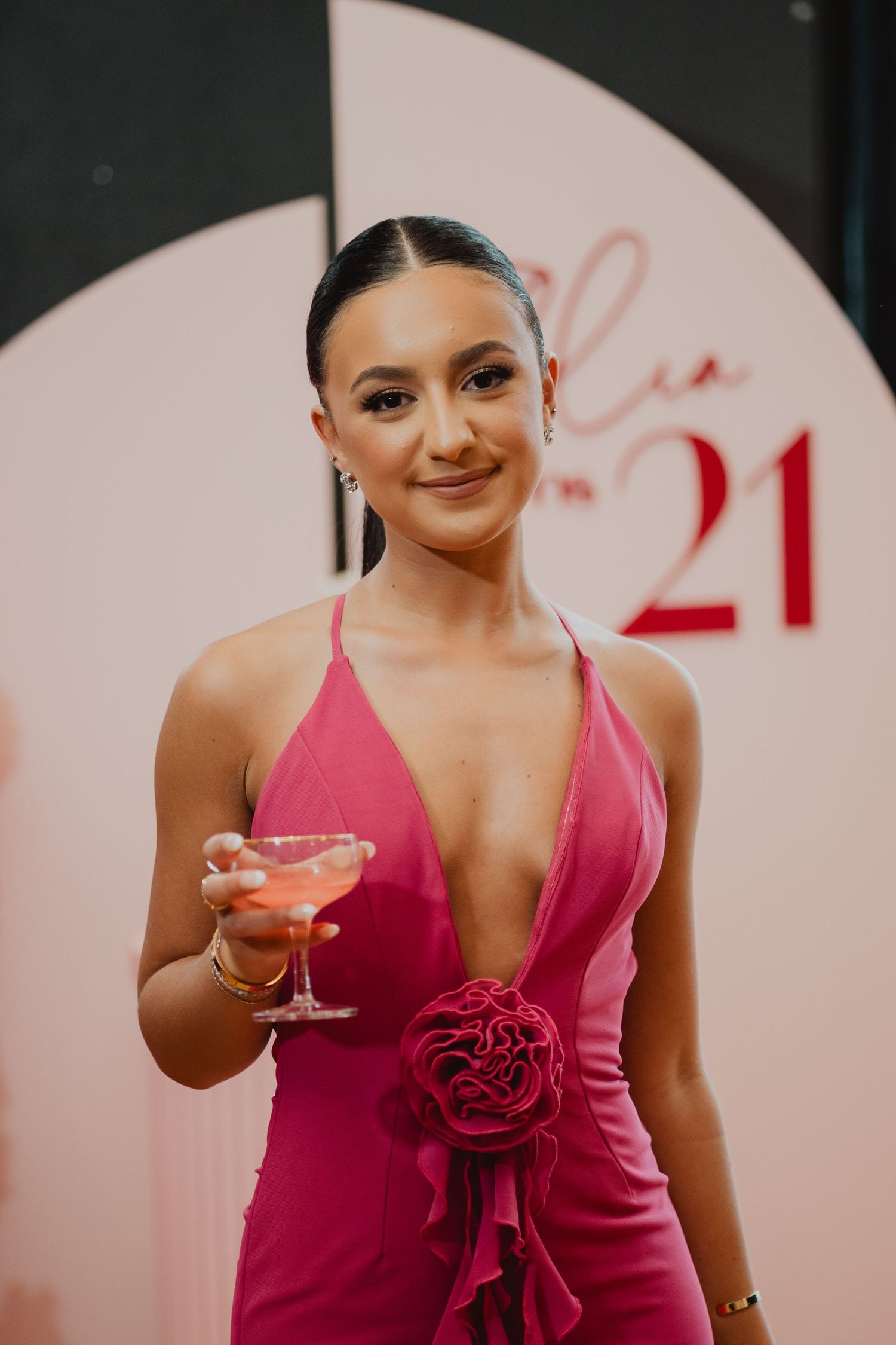 Guest in a pink dress in front of a 21st birthday backdrop in Melbourne