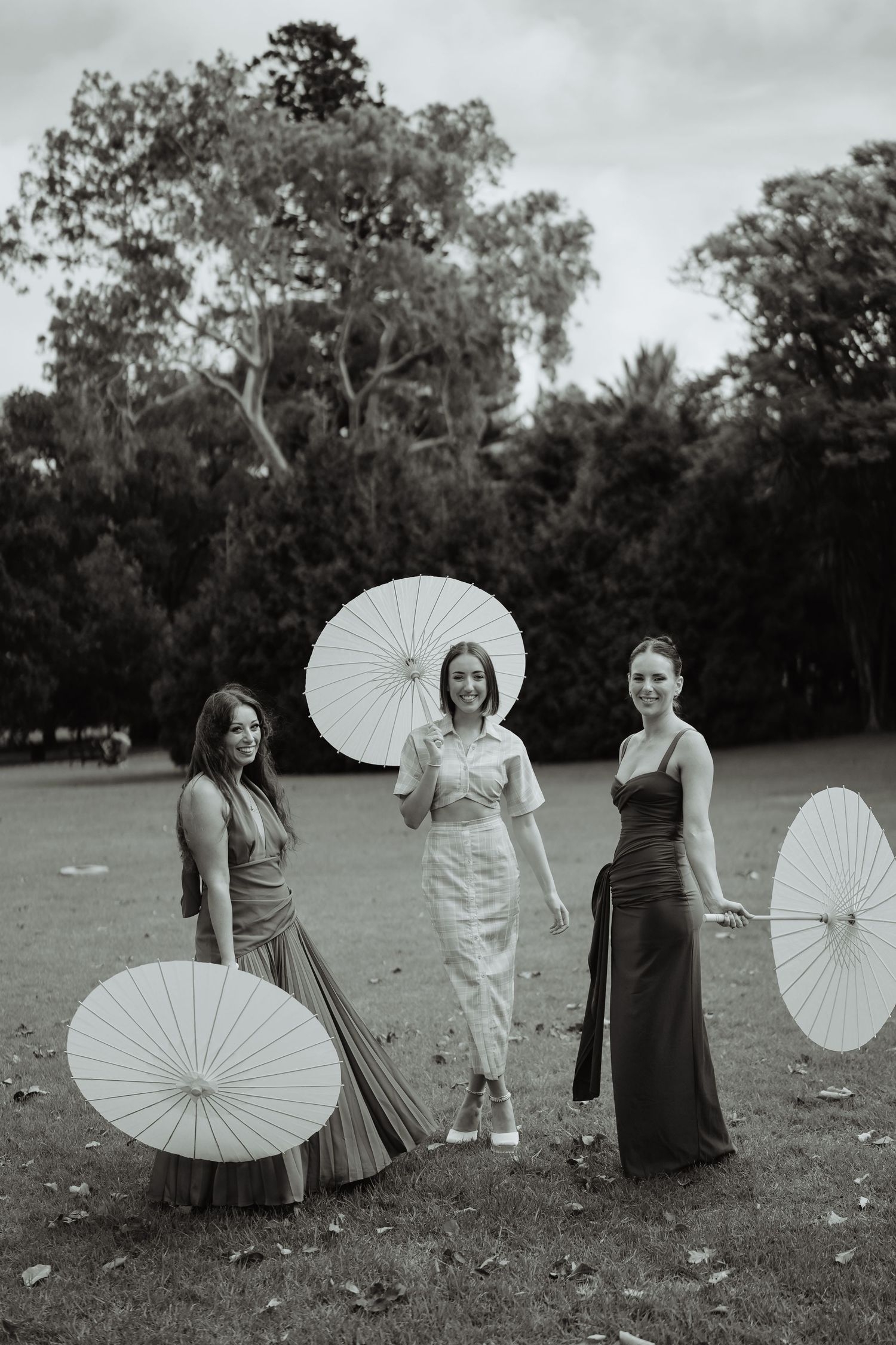 Wedding party holding parasols outdoors, black and white