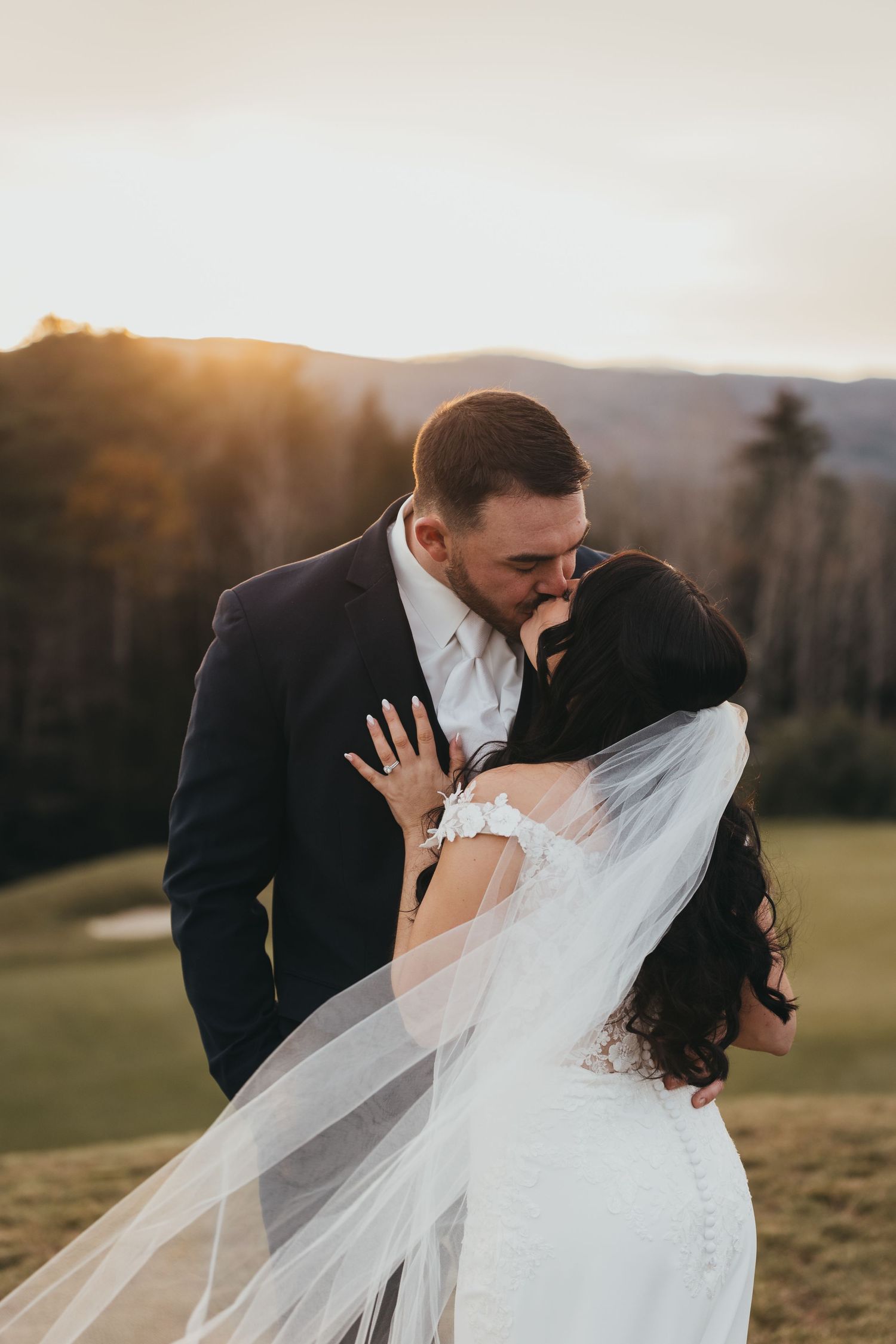 Romantic sunset wedding portrait with flowing veil against mountain backdrop. Owls Nest Resort in the New Hampshire White Mountains.
