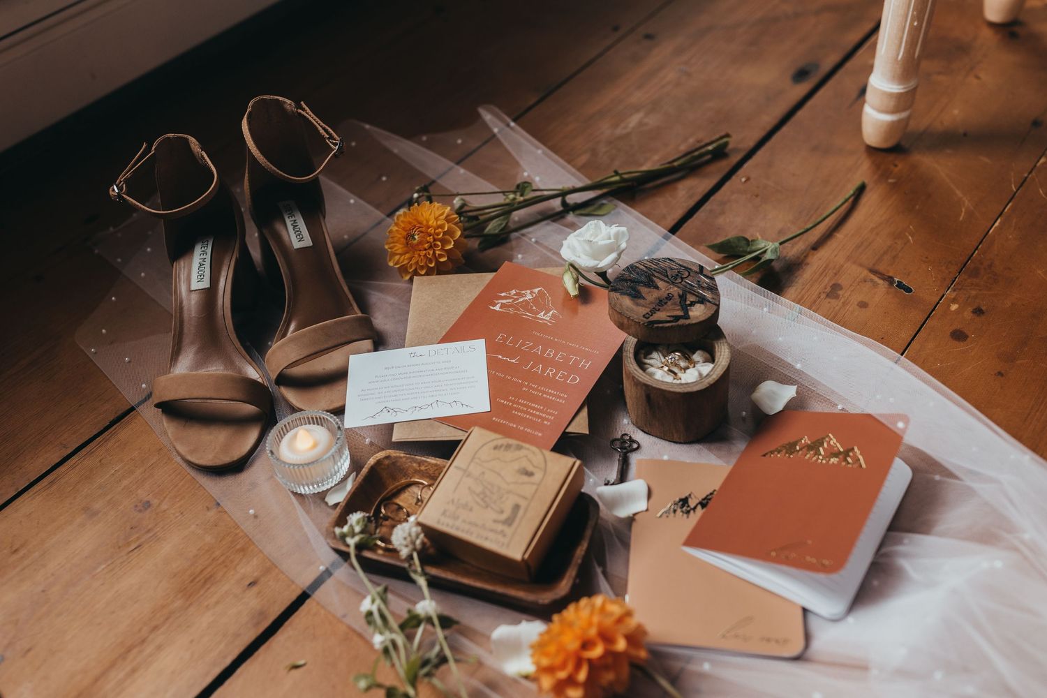Vintage books, glasses, and dried flowers arranged on a rustic wooden table in warm lighting.