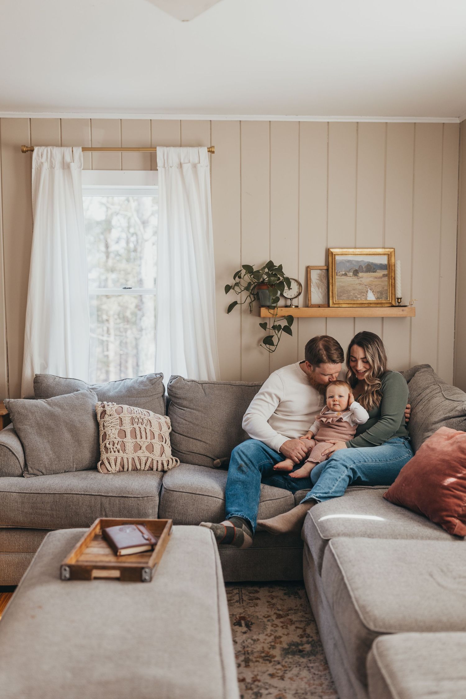 Family relaxing together on a grey sectional couch in a cozy living room.