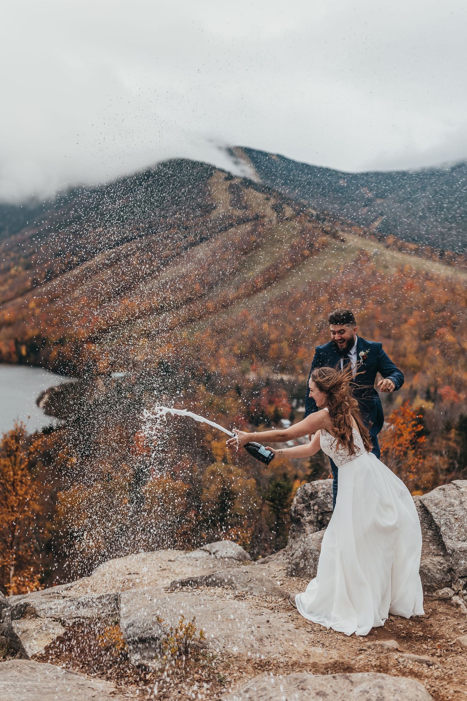 Couple celebrating on mountain peak surrounded by autumn foliage on Artist Bluff Mountain Peak In the White mountains of New Hampshire.