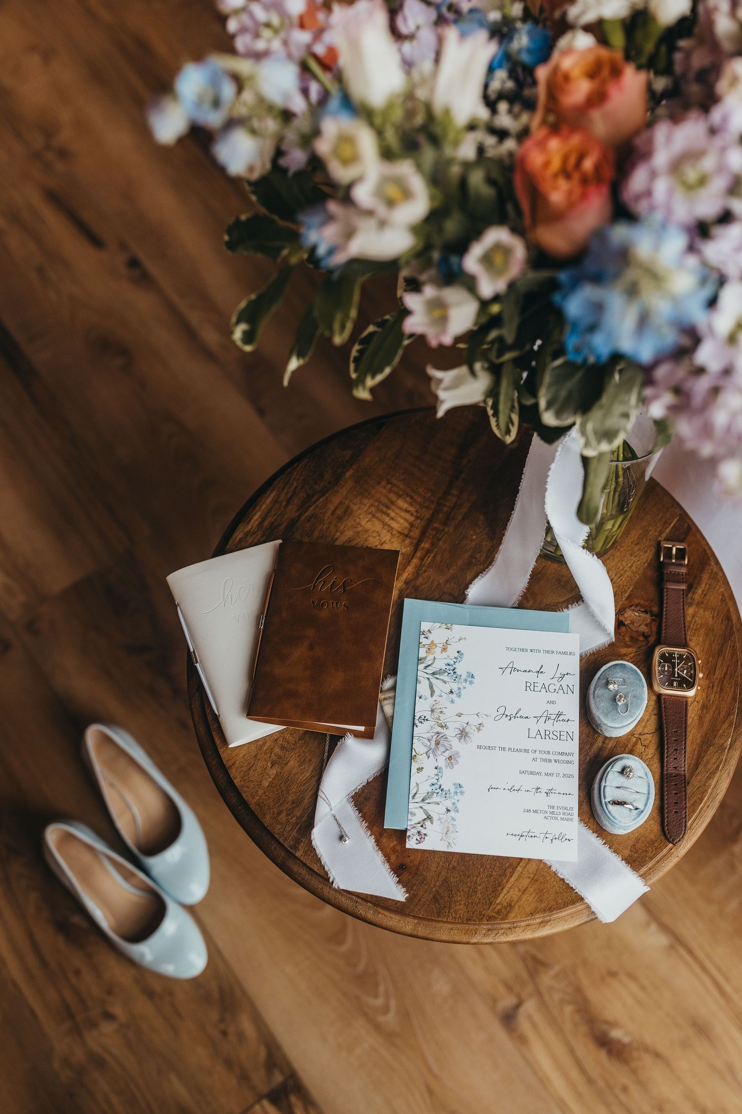 Wedding details including invitations, flowers, and decor arranged on a wooden surface.