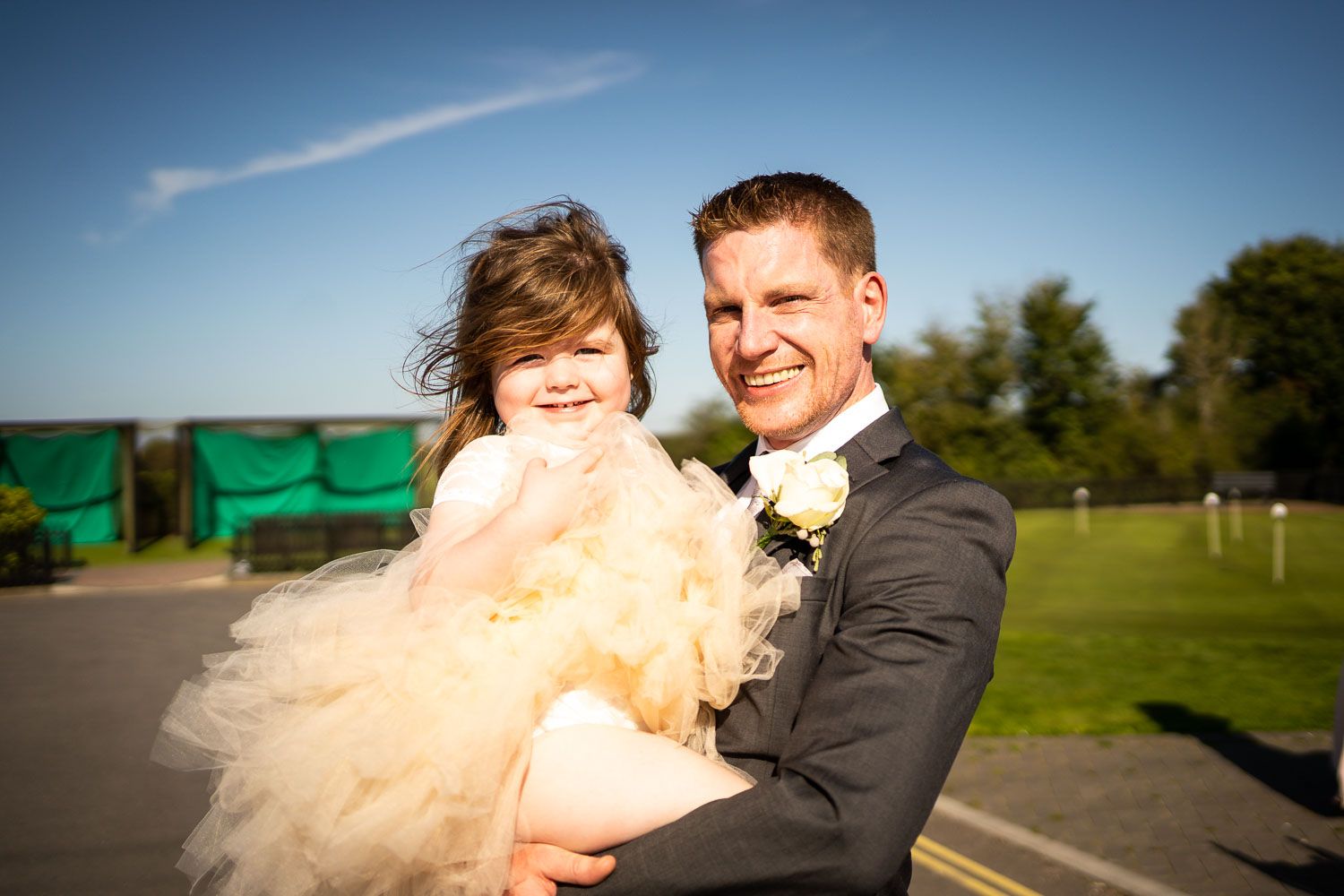 A joyful wedding moment captured outdoors against a bright blue sky on a sunny day.