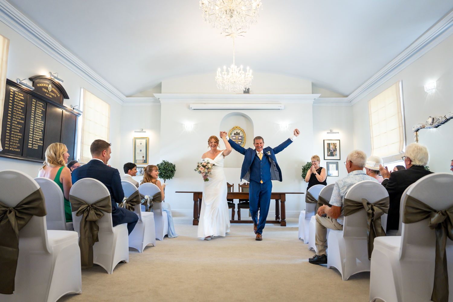 Newlyweds celebrating with raised arms as they walk down the aisle after their wedding ceremony.