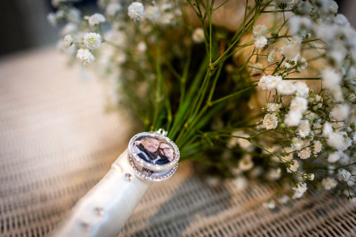 Wedding ring and delicate baby's breath flowers on display against a textured neutral background.