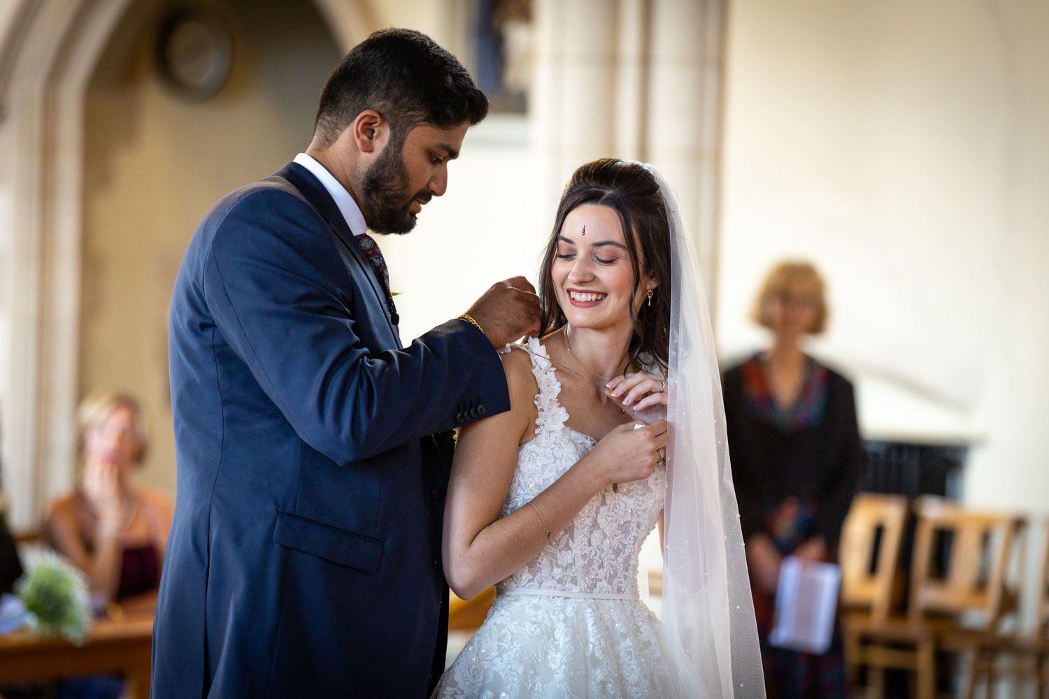 A couple shares a tender moment during their wedding ceremony in an elegant indoor setting.
