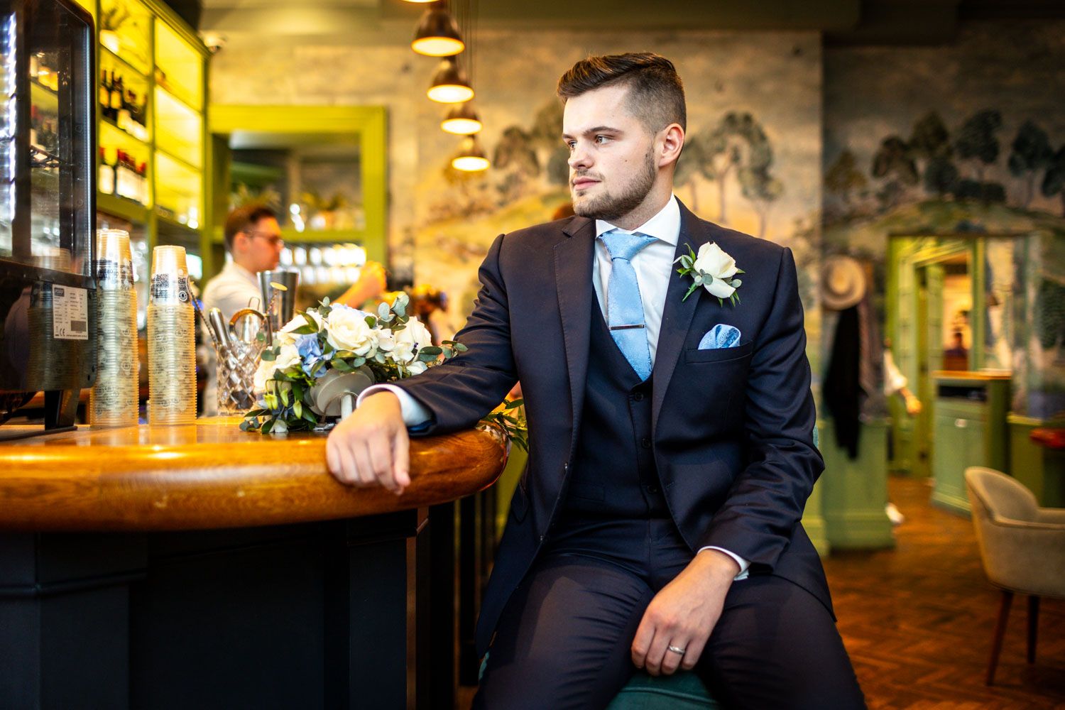Wedding portrait in moody bar setting with vintage decor and warm lighting.