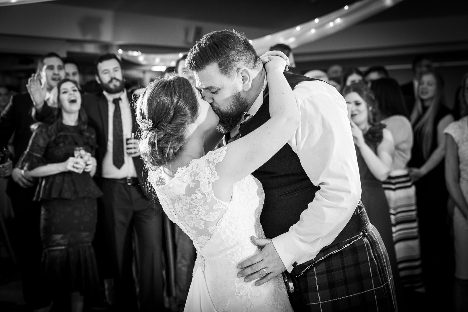 First dance moment at wedding reception with guests watching in background.