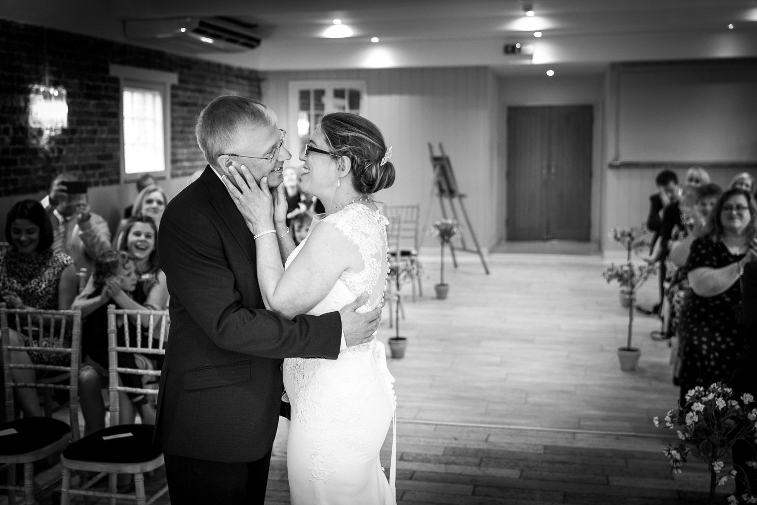 A romantic black and white moment of a dancing couple sharing their first dance at an indoor wedding reception.