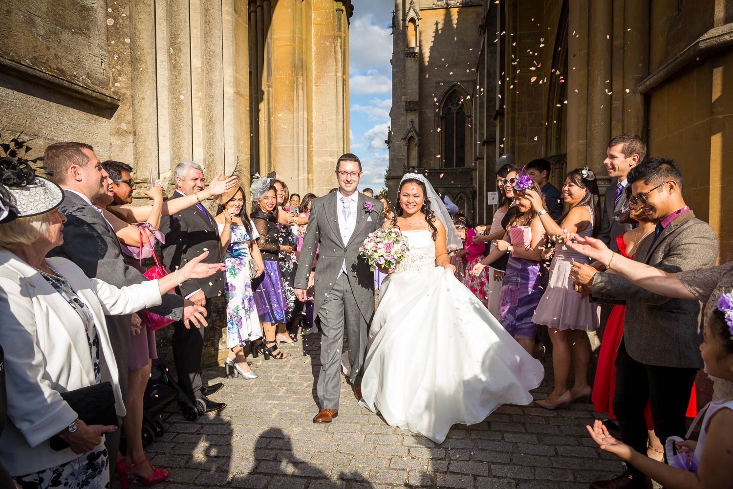 A newlywed couple exits a cathedral while guests shower them with confetti in a joyful celebration.