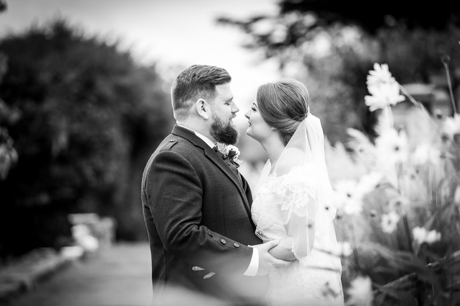 Romantic black and white wedding portrait captured in intimate outdoor garden setting.