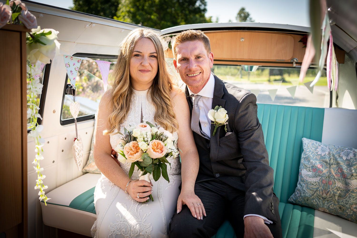 Newlyweds sit together in vintage turquoise and white vehicle with pastel floral bouquet on wedding day.