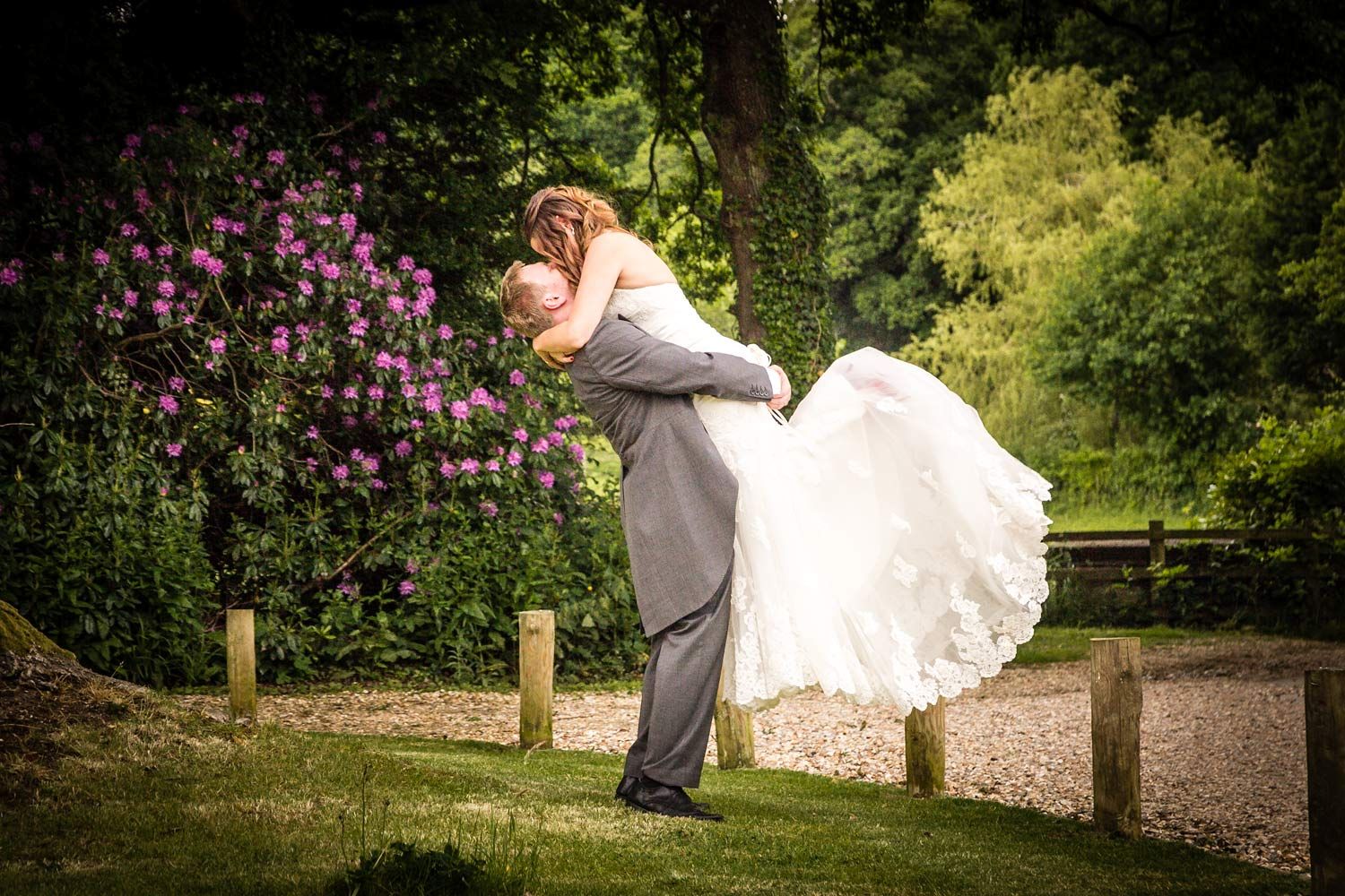 Groom lifting bride in white dress by Southampton wedding photographer John Watson