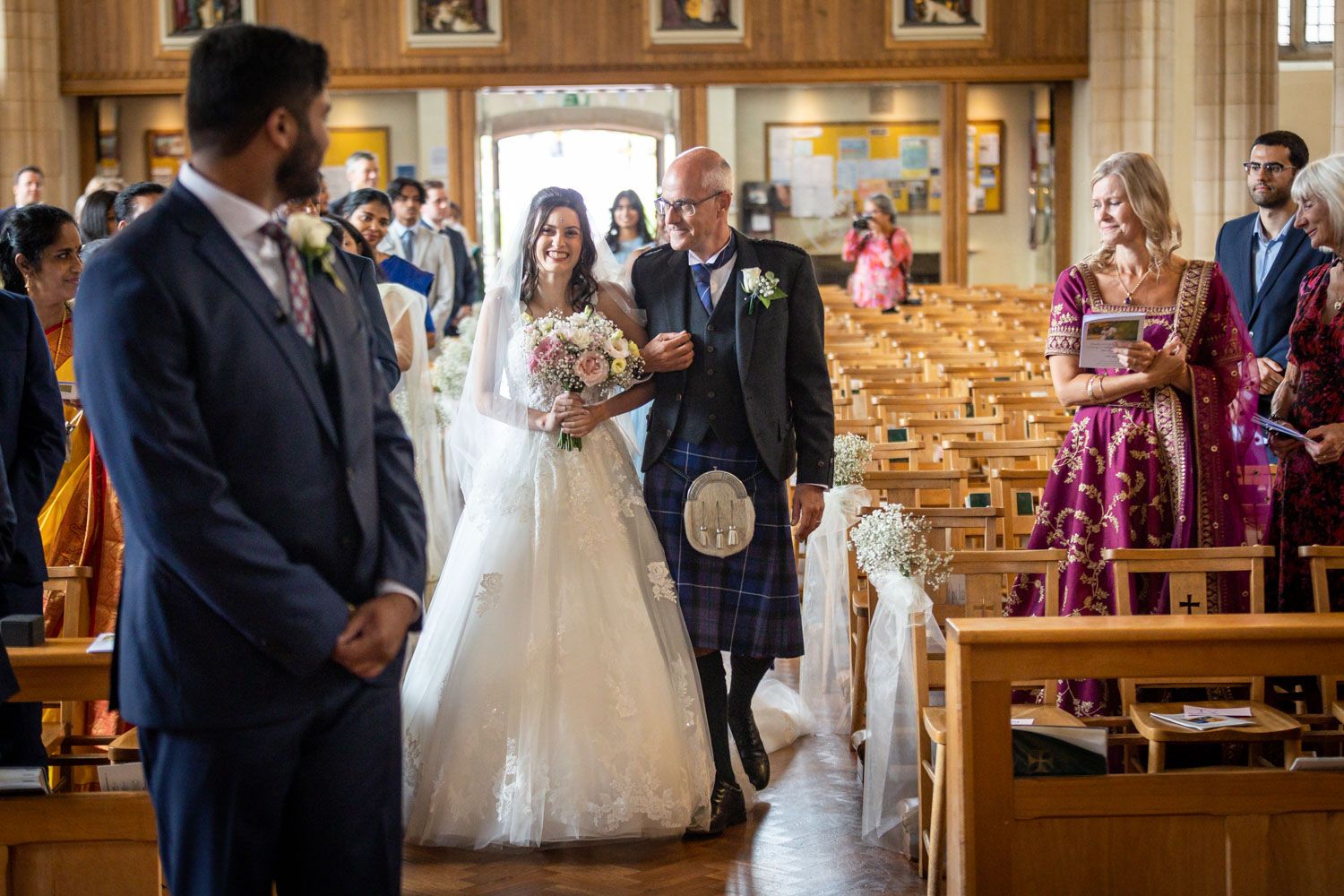 Wedding ceremony taking place in an elegant church with wooden pews and warm lighting during a traditional service.
