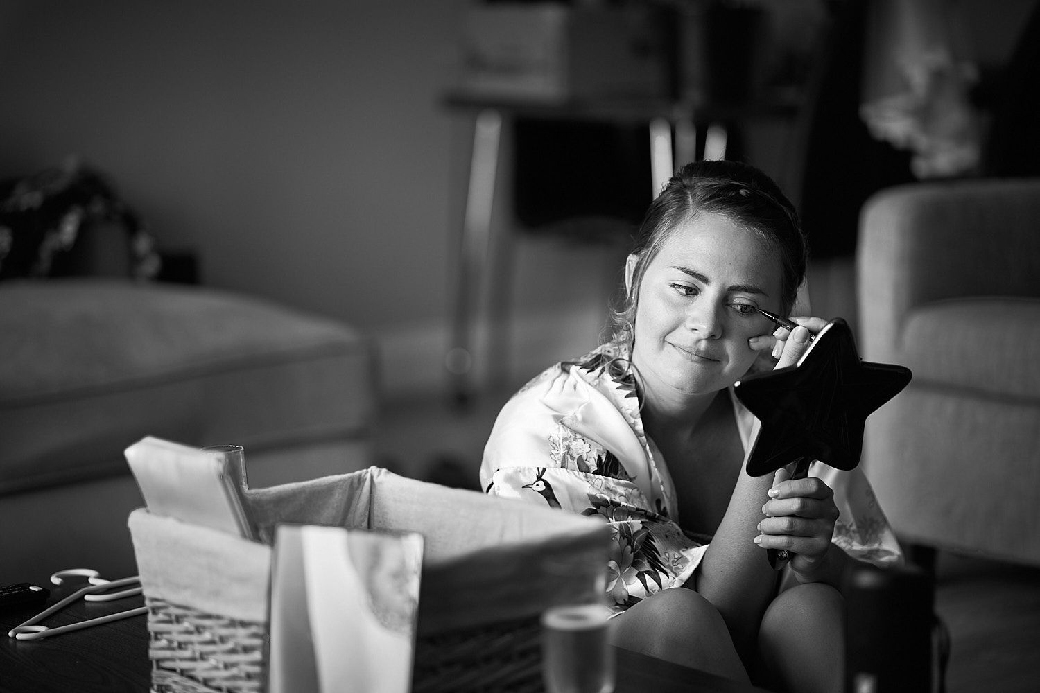 A person in a floral top relaxes on a couch while holding a black cat in a black and white photograph.