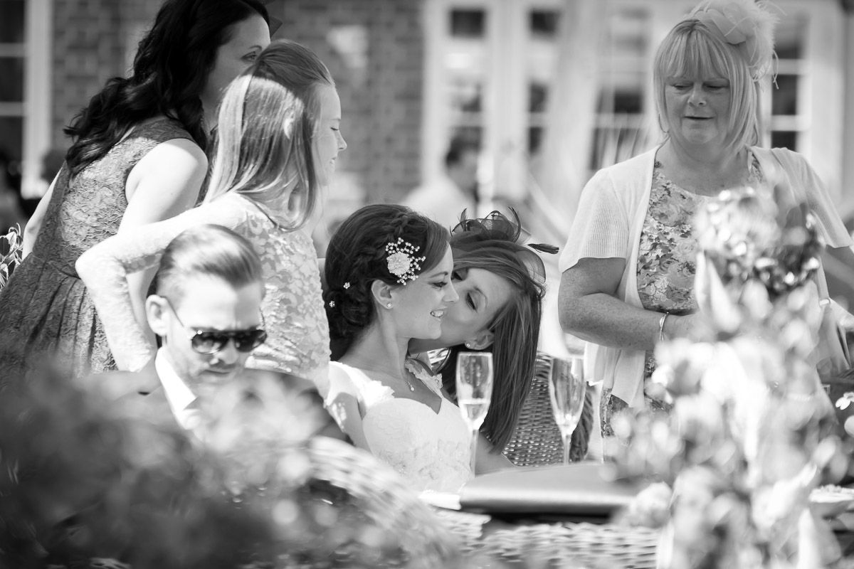 Black and white outdoor candid photo showing friends socializing and enjoying drinks together on a patio.