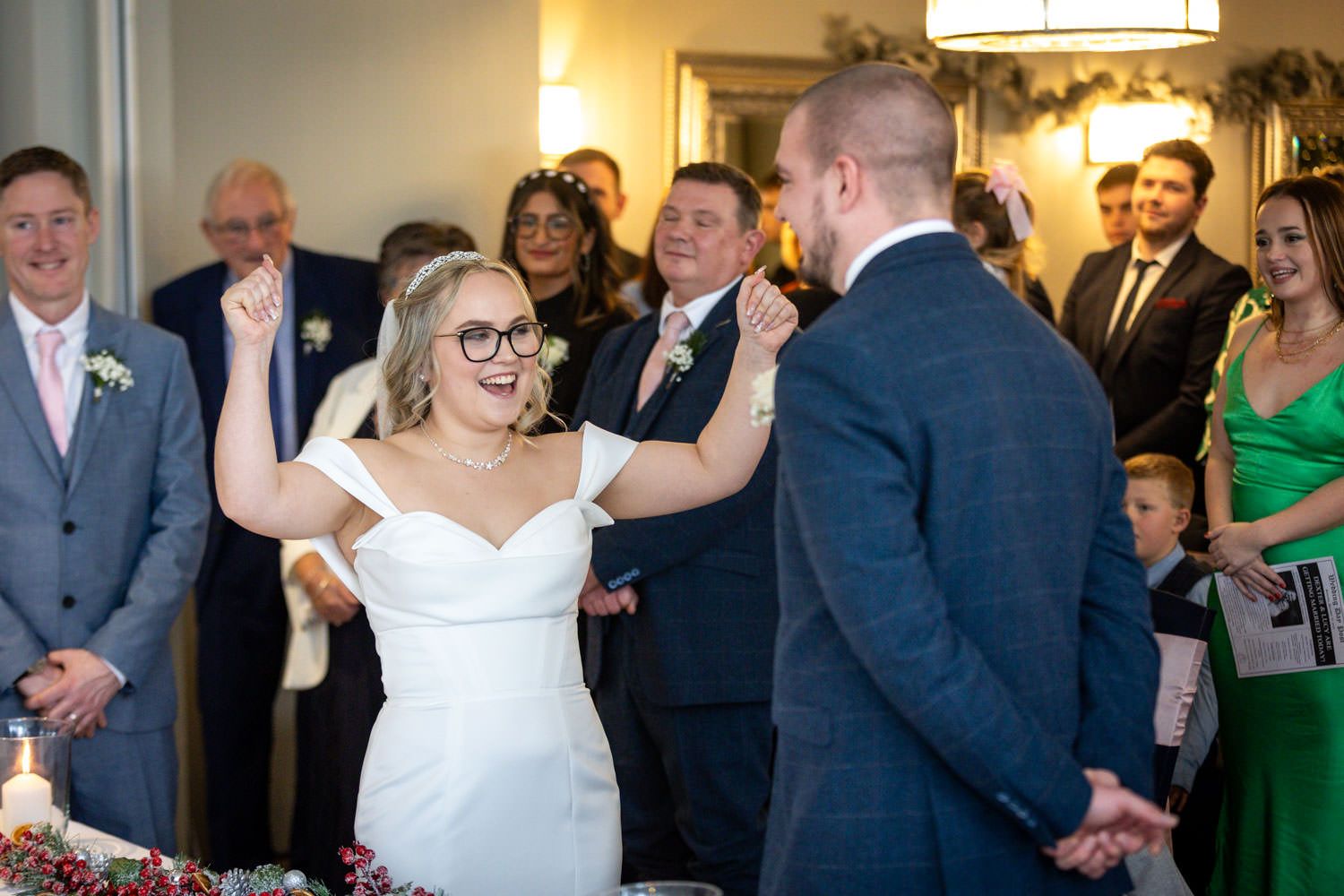 A couple exchanges joyful moments during a wedding ceremony while guests look on smiling.
