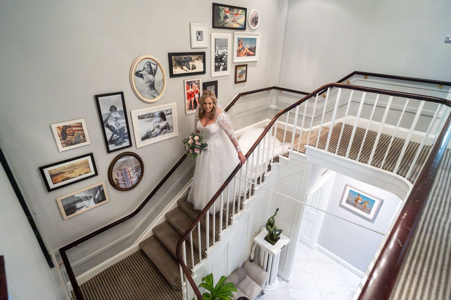 Curved staircase with white railings and gallery wall of framed photos and artwork ascending along the wall.